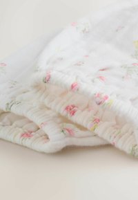 Belo bombažno blago s cvetličnim vzorcem v roza in zeleni barvi. Ima nabran rob in mehko, teksturirano površino.