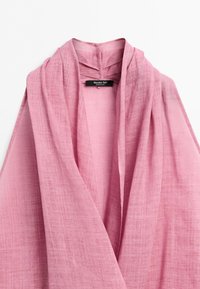 Zachte roze linnen blouse met een sjaalkraag en een zichtbaar zwart merklabel genaaid aan de binnenkant van de halslijn.