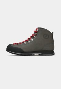 Scarponcino da trekking grigio realizzato in suede durevole, con lacci rossi, occhielli in metallo e una punta in gomma nera. Suola robusta per trazione.