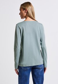 Lange mouwen shirt van zacht, lichtgroen stof met een ronde hals, een soepele textuur, een ontspannen pasvorm en zijsplitten aan de zoom.