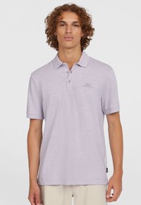 Polo shirt violet clair en tissu texturé, avec un col �à trois boutons et un logo brodé sur la poitrine. Manches courtes.