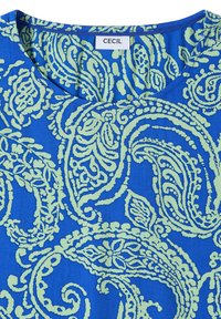 Tissu bleu avec un motif paisley complexe vert clair et un col rond avec une étiquette blanche portant la mention « CECIL » au niveau du col.