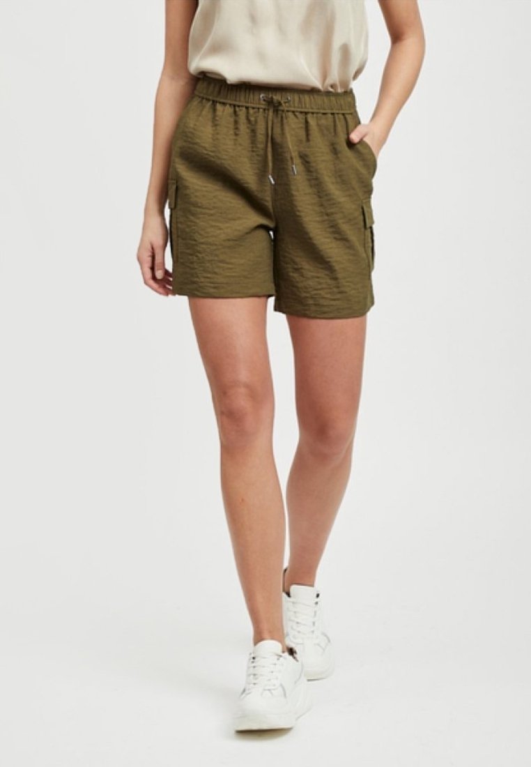 Pantaloni cargo verde oliva con vita elasticizzata, tasche laterali e tessuto testurizzato. Abbinati a sneaker bianche.