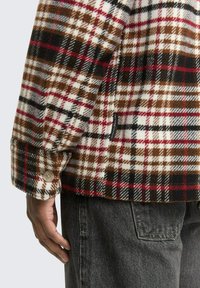 Kariertes Flanellhemd in Rot, Schwarz und Braun, aus weichem Stoff mit einem knöpfbaren Manschette. Es verfügt über ein gewebtes Markenlabel und eine lockere Passform.