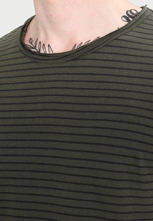 Olivgrön T-shirt med tunna svarta horisontella ränder. Har en rundad halsringning och en något slitna nederkant. Mjuk bomullsmaterial.