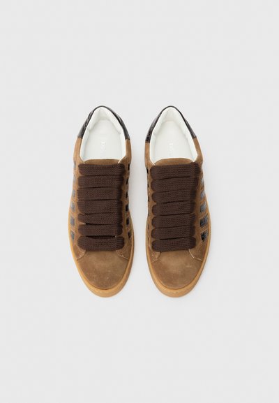 Brown suede sneaker with dark brown lace design, a white interior, and textured accents on the back. Rubber sole with light brown trim.