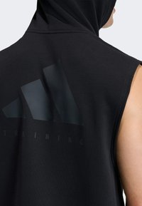 Schwarzer ärmelloser Hoodie aus Baumwolle mit einem großen mattschwarzen Adidas-Logo und dem Wort "TRAINING" auf der Rückseite.