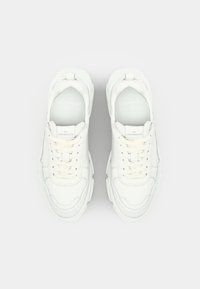 Baskets blanches avec un dessus en cuir lisse, languette rembourrée et lacets. Comprend des coutures courbées et une semelle épaisse et texturée.