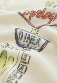 Illustration d'une enseigne de diner rétro avec les mots "Springs DINER" et des lettres empilées formant "SALAD" sur un tissu clair.