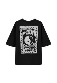 Czarny oversize t-shirt z graficznym nadrukiem zawierającym tekst "SŁOŃCE I TAK WSTAJĘ" w białym kolorze, obrysowanym nieregularnymi wzorami.