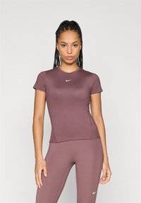 Kortermet maroon treningsgenser med tettsittende design, laget av glatt stoff, med en liten hvit Nike-logo på brystet.