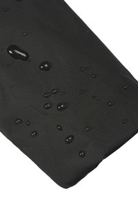 Gocce d'acqua su un tessuto nero con un sottile motivo a righe diagonali, che mostrano la texture di materiale resistente all'acqua o impermeabile.