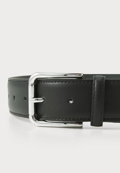 Ceinture en cuir noir avec une boucle en métal argenté brillant, comportant des trous pour le réglage et une texture lisse. Design minimaliste et quincaillerie fonctionnelle.
