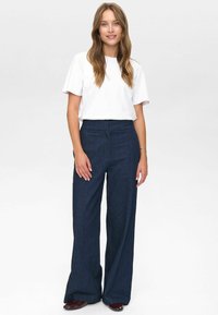 Dark denim, wide-legged trousers paired with a plain white t-shirt. Smooth texture, high-waisted design, and a tailored fit.