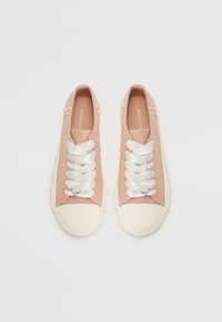 Sneaker di tela rosa con pois bianchi, lacci bianchi e punta in gomma bianca. Texture liscia e design a bassa punta.