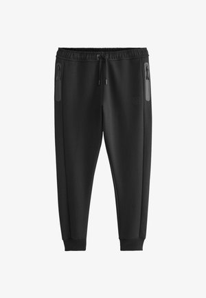 Čierne športové nohavice vyrobené z mäkkého materiálu, s bočnými vreckami na zips a rebrovanými manžetami pre priliehavý vzhľad.