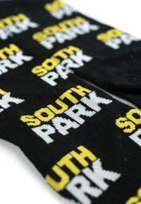 Calzini neri con ripetuto testo "SOUTH PARK" in bianco e giallo. Il materiale appare morbido con una consistenza liscia.