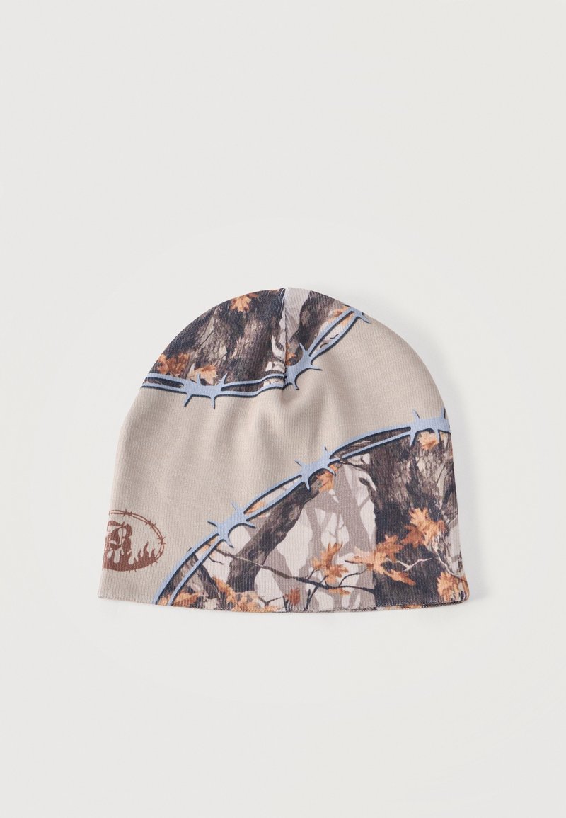 Bonnet avec motif camouflage comprenant des branches d'arbre, des feuilles et du fil barbelé dans des tons beige, marron et bleu.