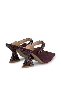 Scarpe di suede viola con punta a taglio, decorate con una fascia che presenta gemme nere e rosse. Tacchi scolpiti unici con un design gioiello.
