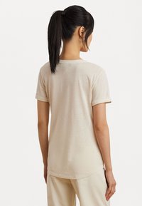 Light beige short-sleeve t-shirt featuring a crew neckline, rolled cuffs, and a relaxed fit, made from soft, textured fabric.