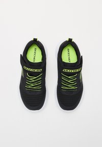 Zapatillas deportivas negras con una parte superior de malla transpirable, acentos en verde neón y cordones elásticos. Suelas de goma blanca y logotipos en las correas.