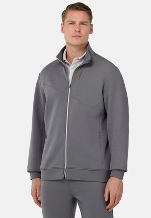 Hall Grey zip-up jakk, millel on kõrge krae ja kontrastpaneel. Omab nähtavaid õmblusi, küljetaskuid ja diskreetset oranži aksenti tõmblukul.