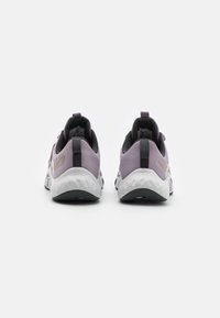 Fioletowe siatkowe trampki z białą i czarną podeszwą, z czarnym akcentem na pięcie, wyściełanym kołnierzem i tylną pętlą ułatwiającą zakładanie.