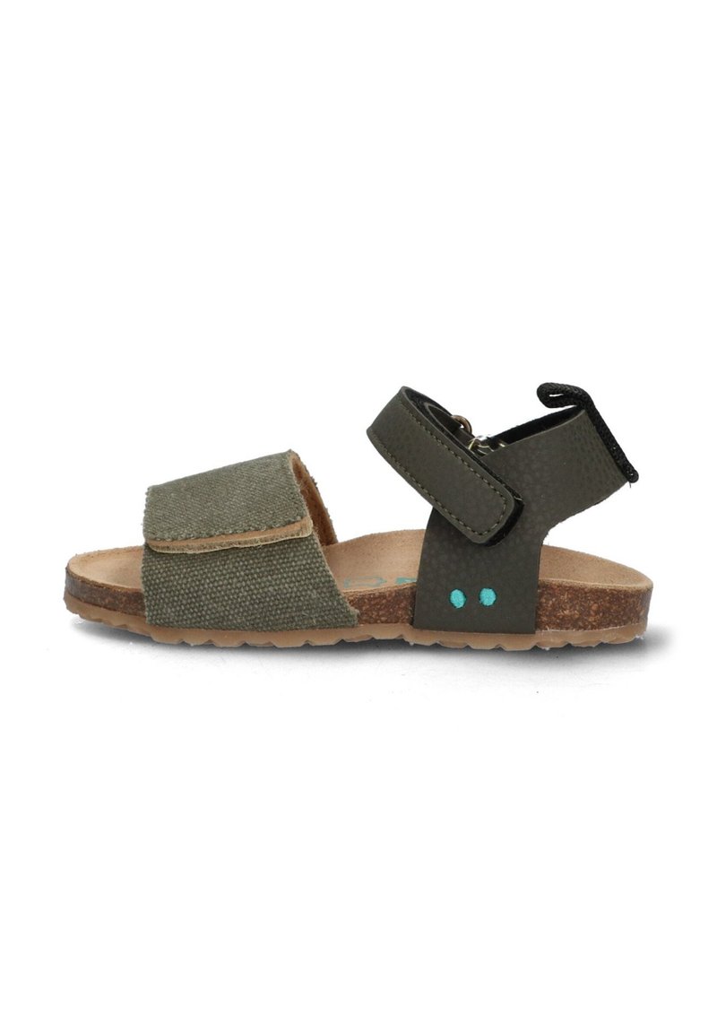 Grön kanvas-sandal med kork-sula, utrustad med en bred tygrem och en justerbar rem med spänne. Två blå accenter på sidan.