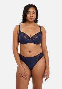 Ensemble de lingerie bleu marine comprenant un soutien-gorge avec balconnets, bordé de dentelle, et un slip à panneaux en dentelle assorti, en matériau doux et avec des bretelles ajustables.