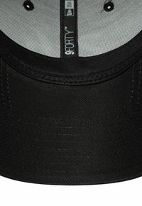 Schwarze Kappe mit gebogenem Schirm, gefertigt aus strukturiertem Stoff. Innen hat sie ein hellgraues Futter und ein Markenetikett. Die Nähte sind am Rand sichtbar.