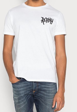 White cotton t-shirt with short sleeves and a round neckline, featuring a black graphic logo on the left chest and a relaxed fit.