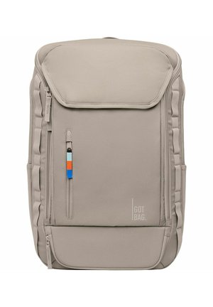 Beige fabric backpack with a flap closure, side zipper pocket, and colored accent. Features padded sides and a subtle brand logo.