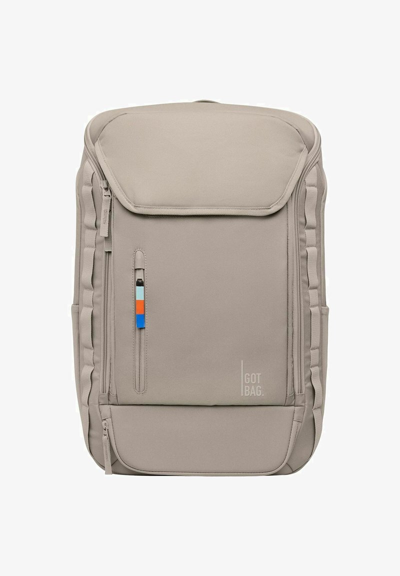 Mochila de tela beige con cierre de solapa, bolsillo con cremallera lateral y acentos de color. Cuenta con laterales acolchados y un sutil logotipo de la marca.