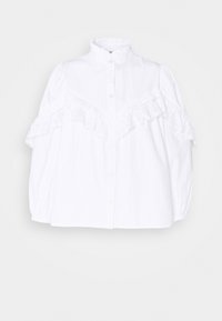 Chemise blanche boutonnée avec un col montant, dotée d'accents à volants et de détails brodés sur les manches pour ajouter de la texture et un intérêt au design.