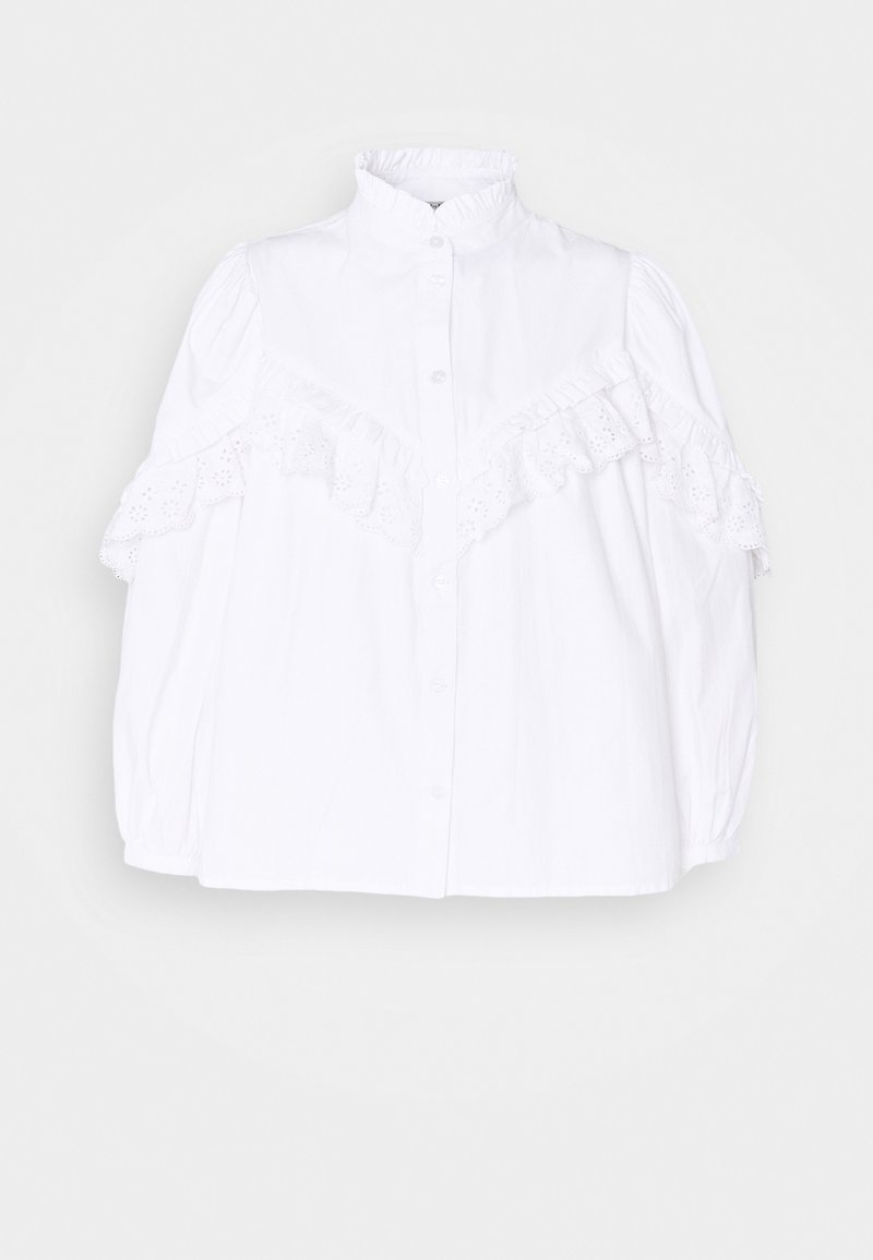Chemise blanche boutonnée avec un col montant, dotée d'accents à volants et de détails brodés sur les manches pour ajouter de la texture et un intérêt au design.