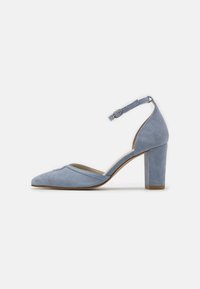 Zapato de tacón alto de ante azul claro con punta afilada, correa en el tobillo y tacón grueso. Textura suave con un sutil detalle de costura a lo largo del borde.