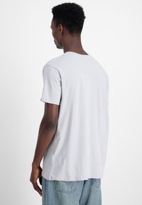 Gaišpelēka īsām piedurknēm T-kreklu, kas izgatavots no kokvilnas, ar apaļu izgriezumu un brīvu piegriezumu. Aizmugure ir vienkārša ar nedaudz noapaļotu apakšu.