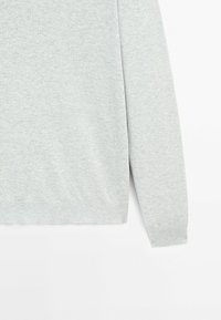 Jasnoszary sweter, teksturowana tkanina, okrągły dekolt, długie rękawy, ściągacze na mankietach i u dołu. Prosty, minimalistyczny design z miękkim wykończeniem.