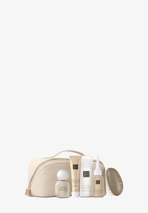 Trousse de toilette beige avec cinq produits de soins capillaires incluant parfum pour cheveux, shampooing, shampooing sec, sérum et une brosse à cheveux.