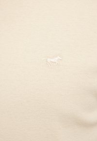 Beiger Baumwollpullover mit strukturiertem Strick. Ein kleines, gesticktes Pferdelogo befindet sich auf der oberen linken Seite.