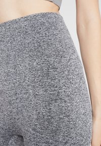 Szare legginsy z wysokim stanem, wykonane z fakturowanej dzianiny, z połączeniem ciemnoszarych i jasnoszarych wzorów. Gładkie wykończenie.