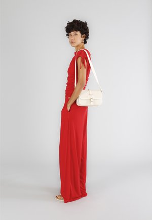 Rød jumpsuit med tætsiddende top og bred ben-silhuet; båret med en cremet crossover-taske. Glat stof, minimalistisk design og korte ærmer.