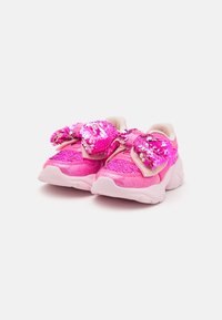 Rosa joggesko med paljetterte sløyfer, teksturert overdel og en tykk hvit såle. Har glitrende detaljer og en kontrasterende beige innersåle.