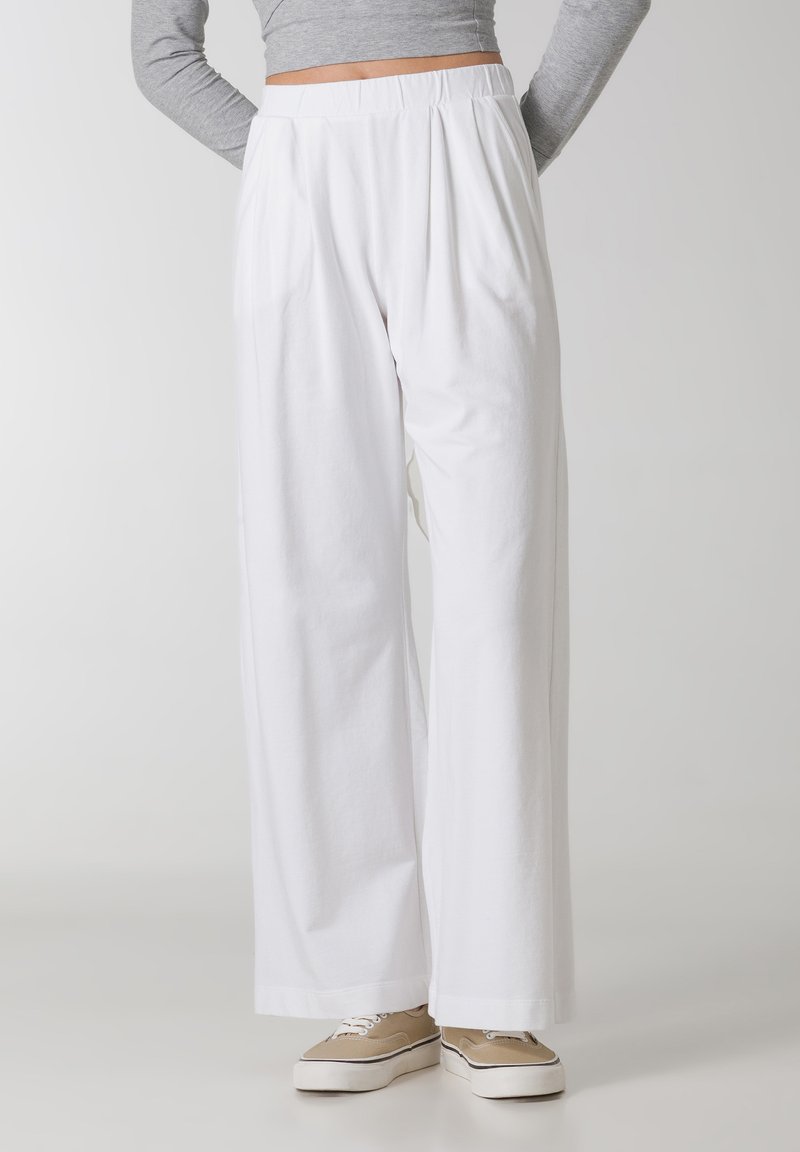 Pantaloni albi cu picioare largi, cu un fațetat în față și talie elastică. Fabricat dintr-un material ușor. Asortați cu adidași bej.