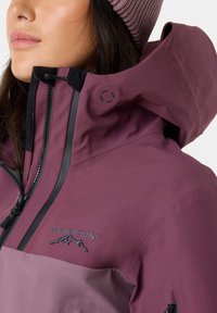 Purple waterproof jacket with a high collar, black accents, attached hood, and zipper detail. Features embroidered logo on the chest.