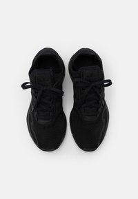 Baskets de sport noires avec une tige en maille, bout arrondi, lacets plats et semelle texturée. Design minimaliste avec un branding discret.