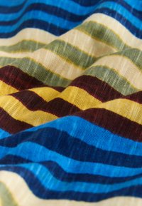 Tissu doux à rayures horizontales en bleu, jaune, bordeaux, vert et crème, présenté en gros plan avec des plis tricotés texturés.