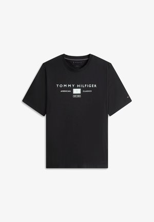 Μαύρο κοντομάνικο μπλουζάκι Tommy Hilfiger με λευκό κείμενο "TOMMY HILFIGER AMERICAN CLASSICS EST. 1985" και μικρό λογότυπο στο αριστερό μανίκι.