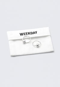 Zilveren creolen met een ronde kraalaccent, gepresenteerd in een witte stoffen zak met het label "WEEKDAY" in vetgedrukt zwart.