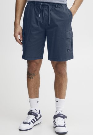 Tumši zili kravas šorti no viegla auduma ar elastīgu jostu, sānu kabatām un nelielu zīmola uzrakstu uz sāniem.